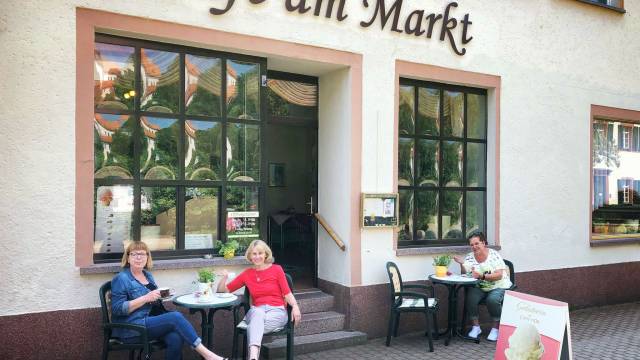 Mitarbeiter des Cafés sitzen vor dem Caféeingang